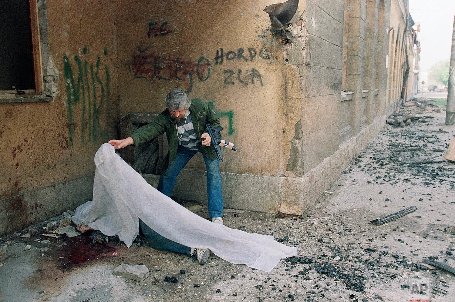 A Muslim militiaman covers the body of a person killed yesterday during fierce fighting between the Muslim militia and the Yugoslav federal army in central Sarajevo on Sunday, May 3, 1992. Bosnian officials and the Yugoslav army bargained Sunday ove…